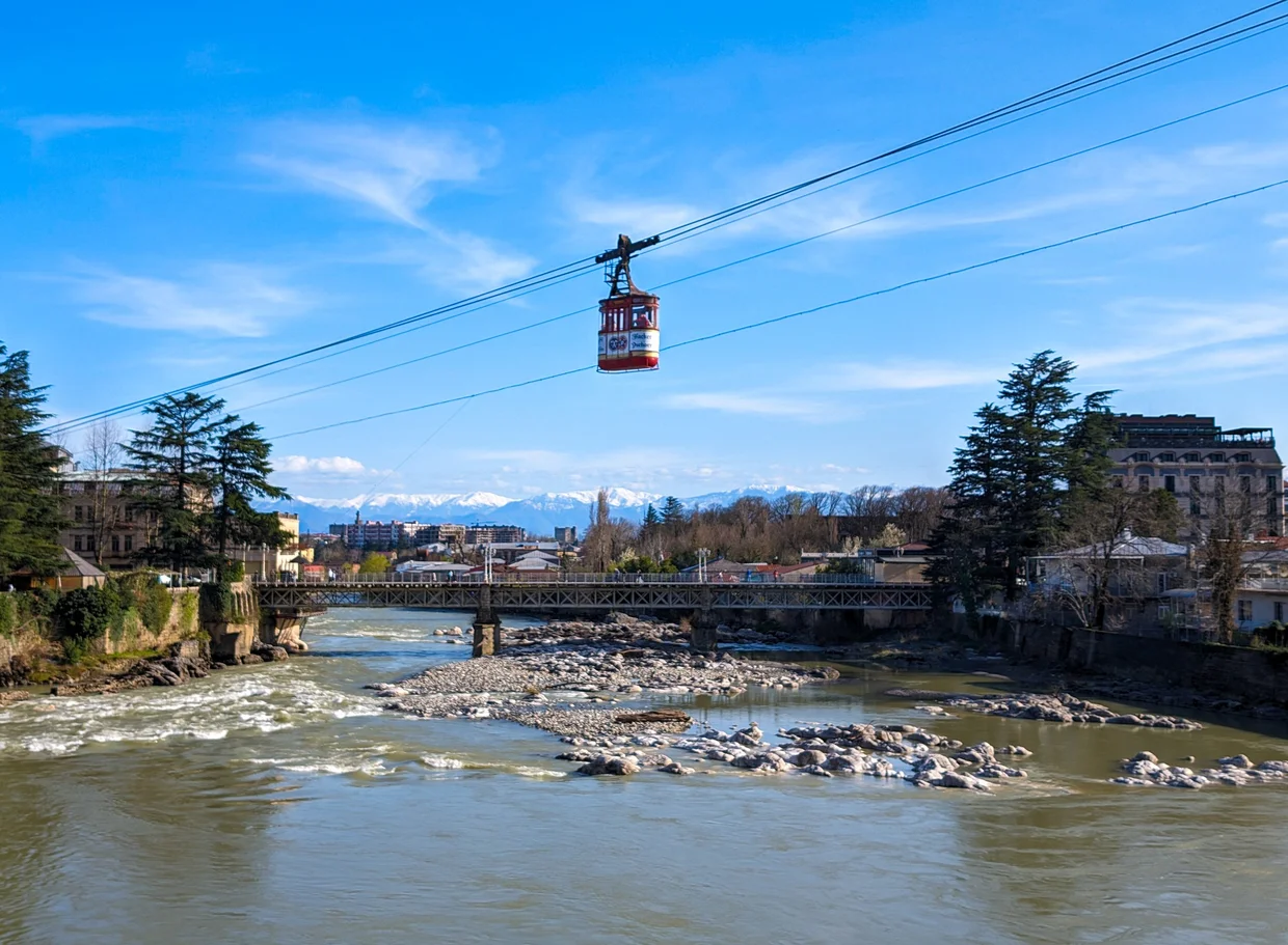 Kutaisi cable car over the Rioni river, the snowy Caucasus peaks sitting behind the city