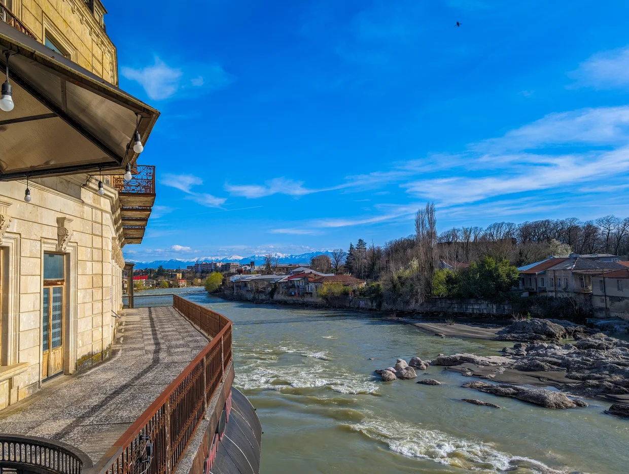 Kutaisi riverfront building with snowy Caucasus peaks behind