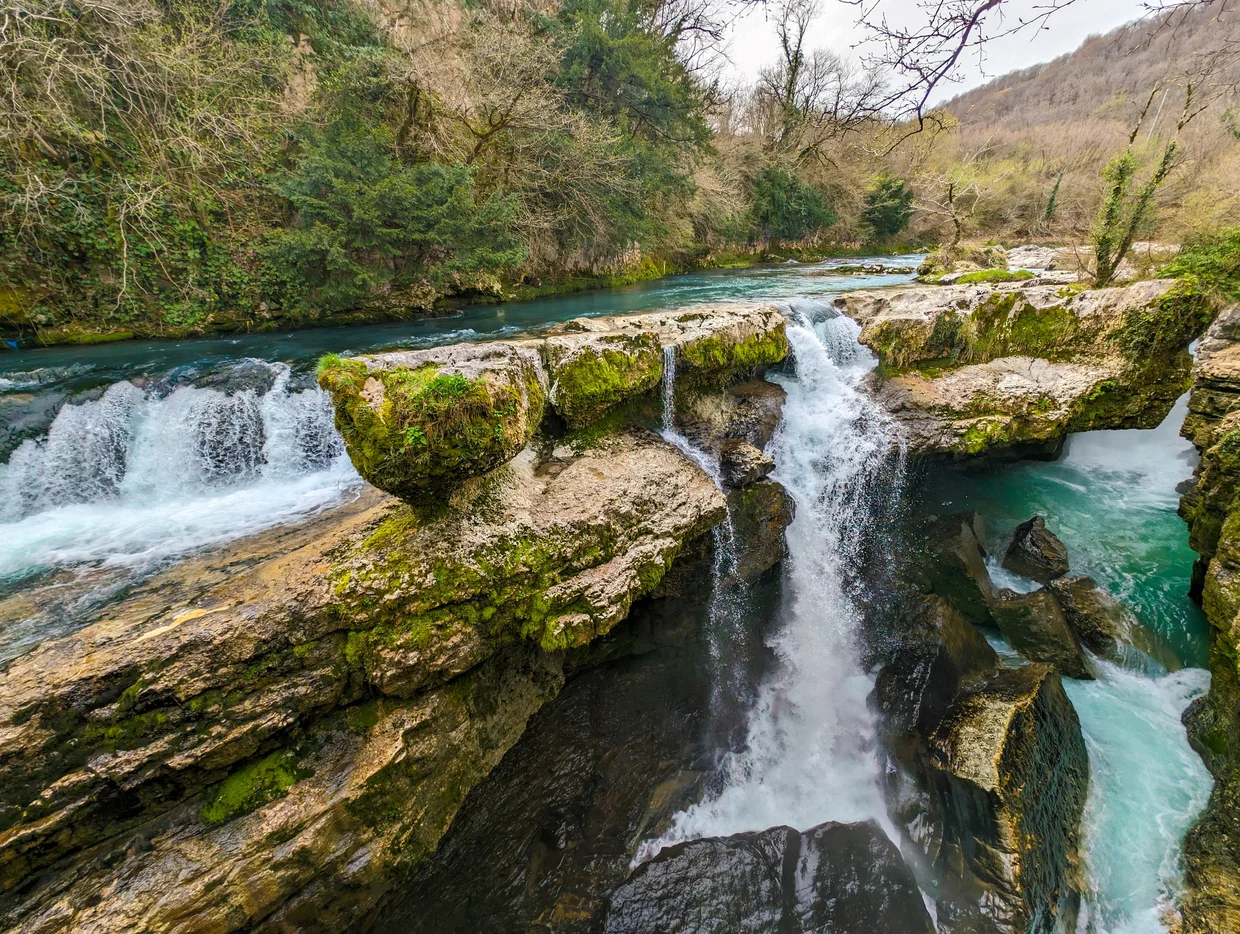 Waterfall cascading over mossy rocks into a turquoise pool