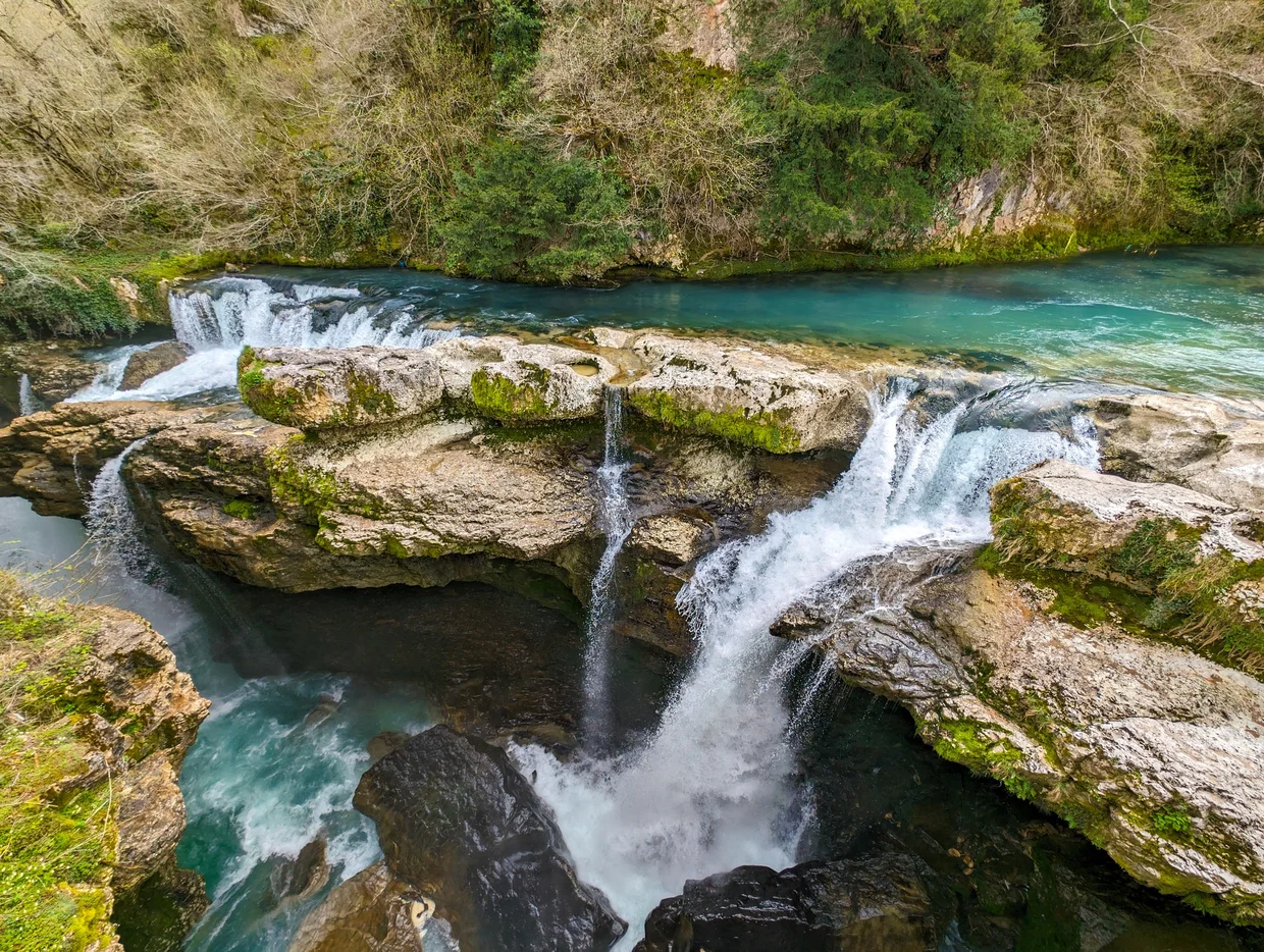 Multiple waterfalls and a turquoise pool, viewed from above