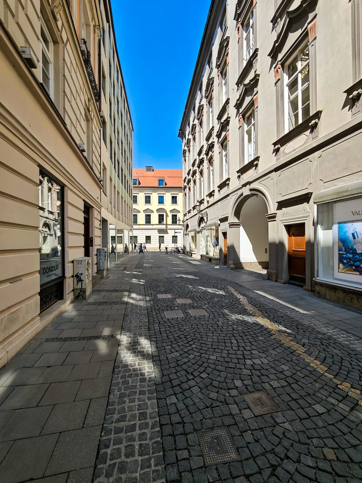 A quiet cobblestone Gasse near Salvatorplatz with sun shadows on the pavement