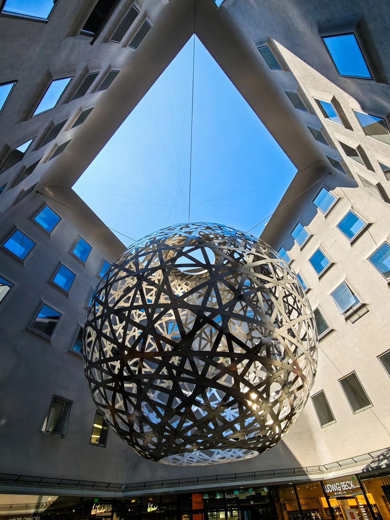 Suspended metal sphere installation in an atrium courtyard at Fünf Höfe