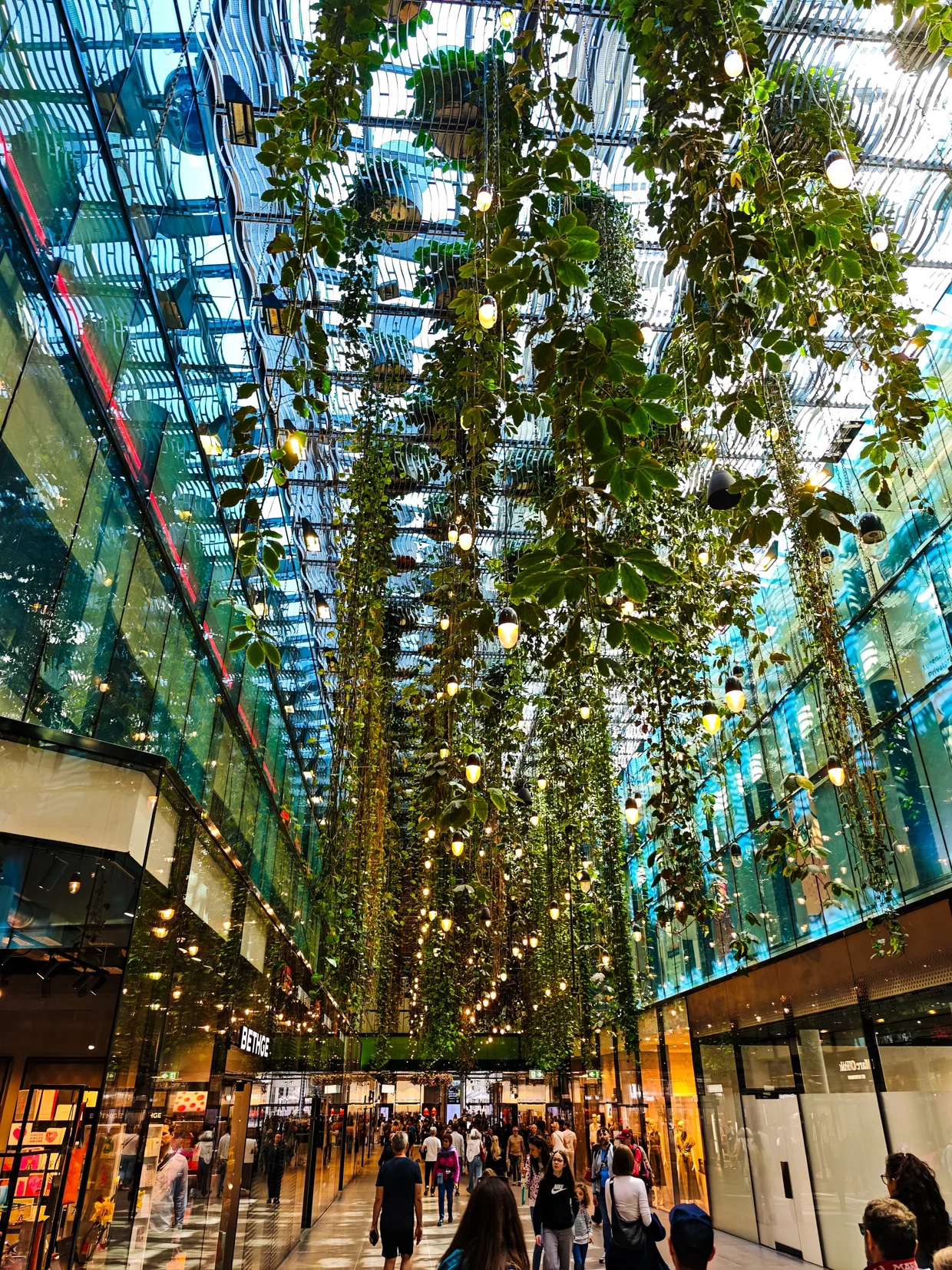 Atrium at Fünf Höfe with cascading hanging plants and pendant lights forming a vertical garden