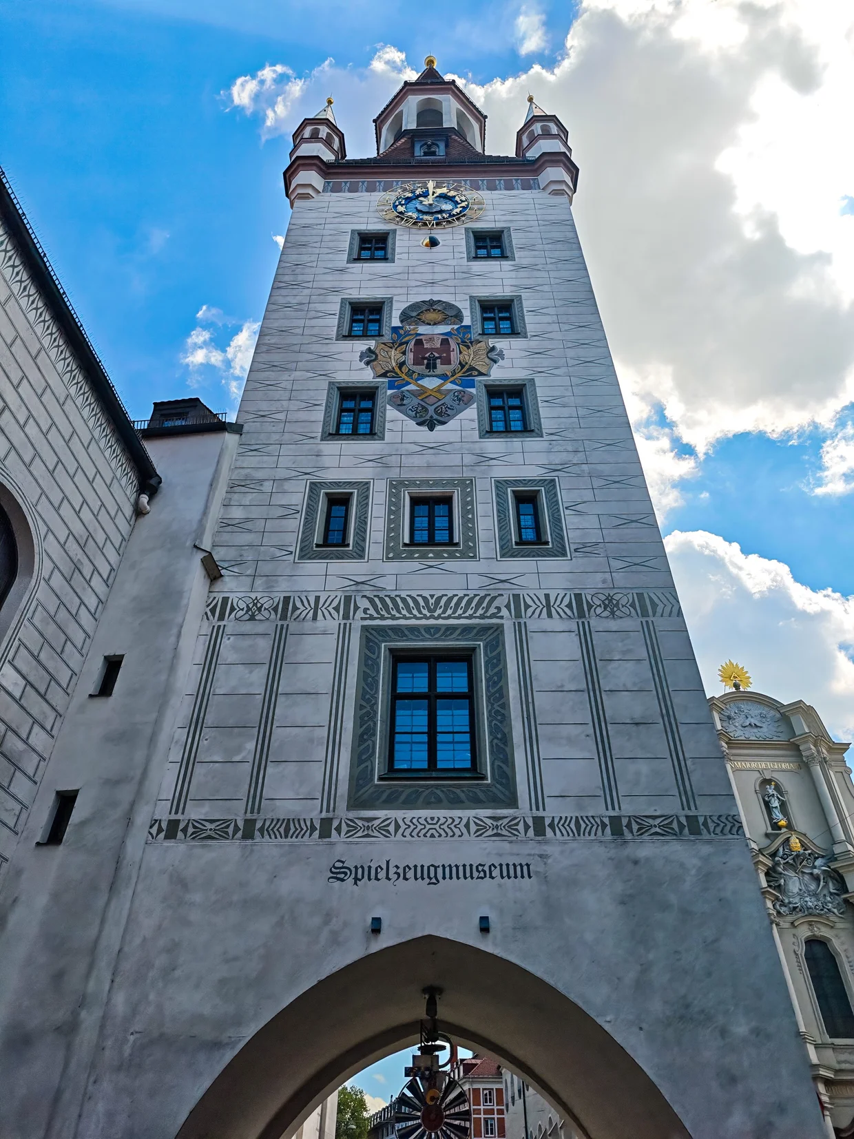 The Spielzeugmuseum tower close up with the painted clock and shields
