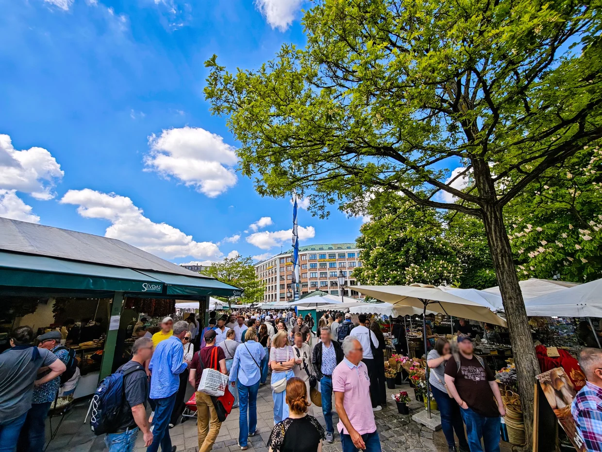 Crowd between market stalls at Viktualienmarkt under blue sky
