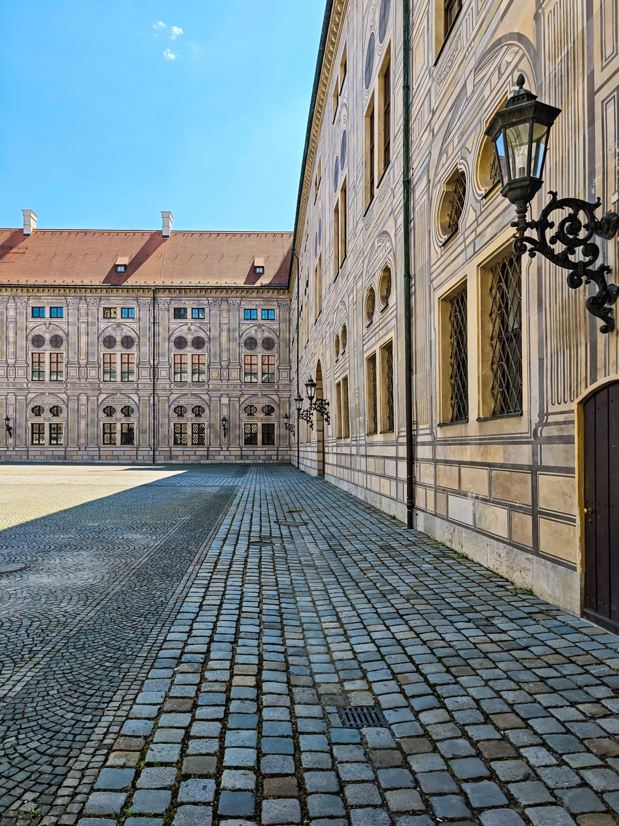 Cobblestone Residenz side passage with a Renaissance facade and lantern