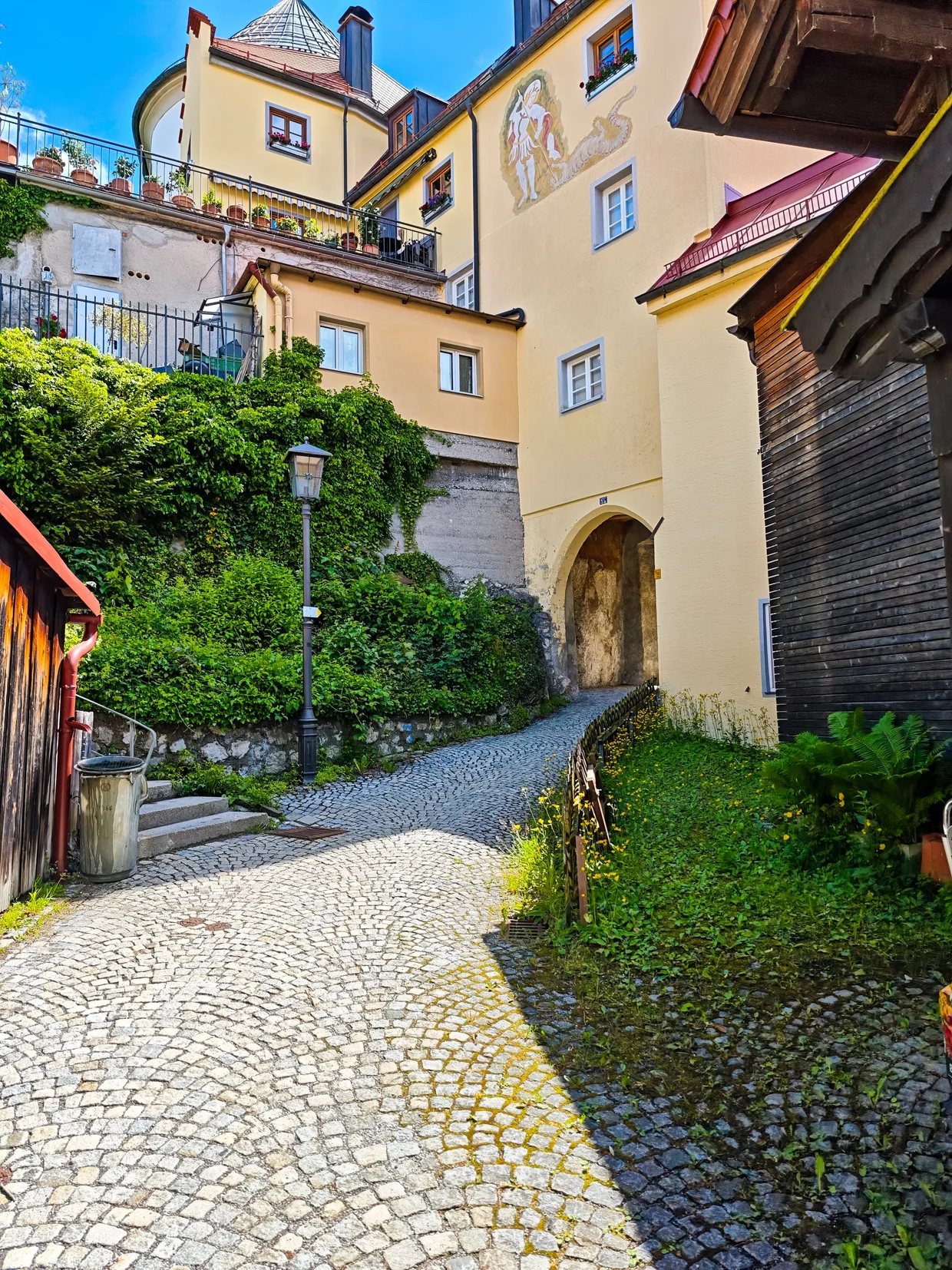 The cobbled path up to a frescoed gate building below the castle