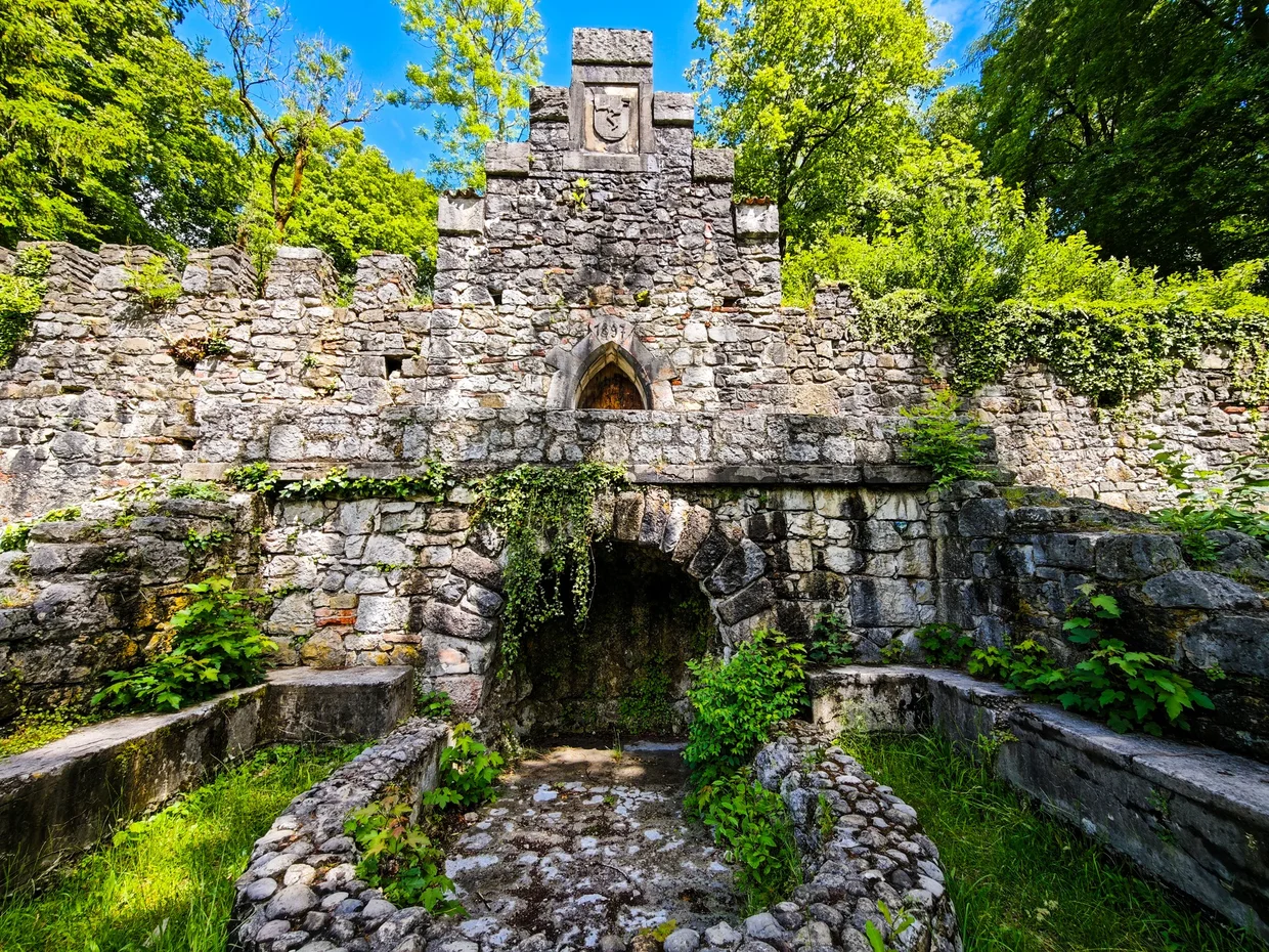 The old stone grotto fountain with its coat of arms