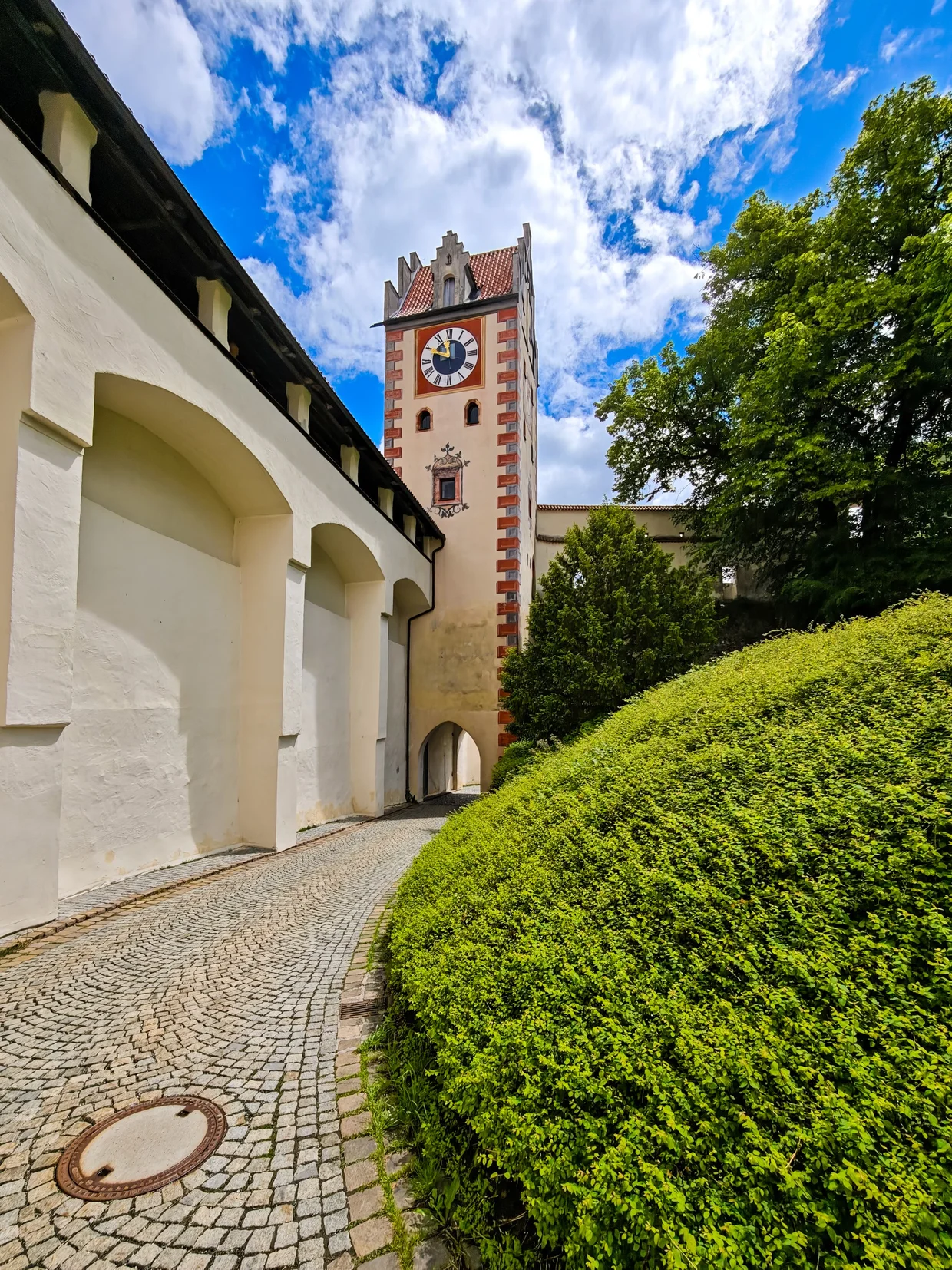 The clock tower and arcade wall along the cobbled castle path