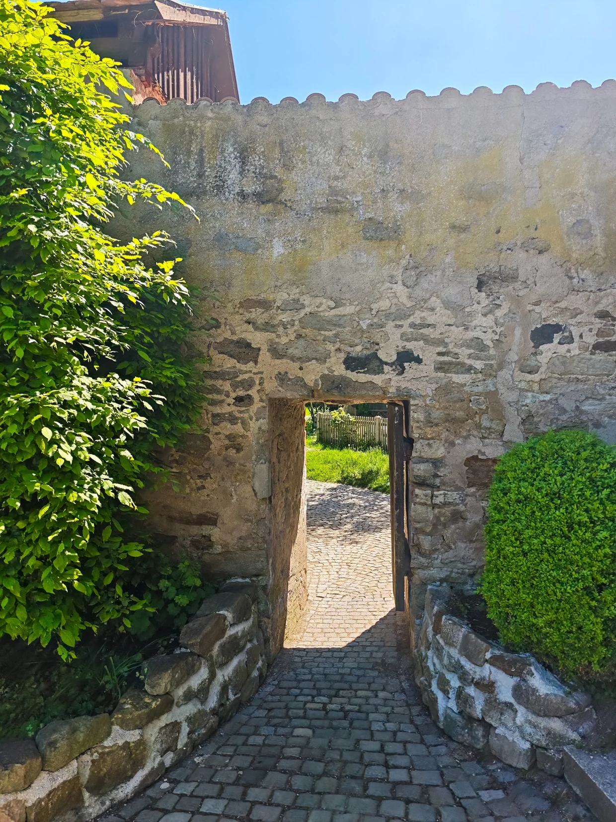 Stone gate in the city wall opening into garden