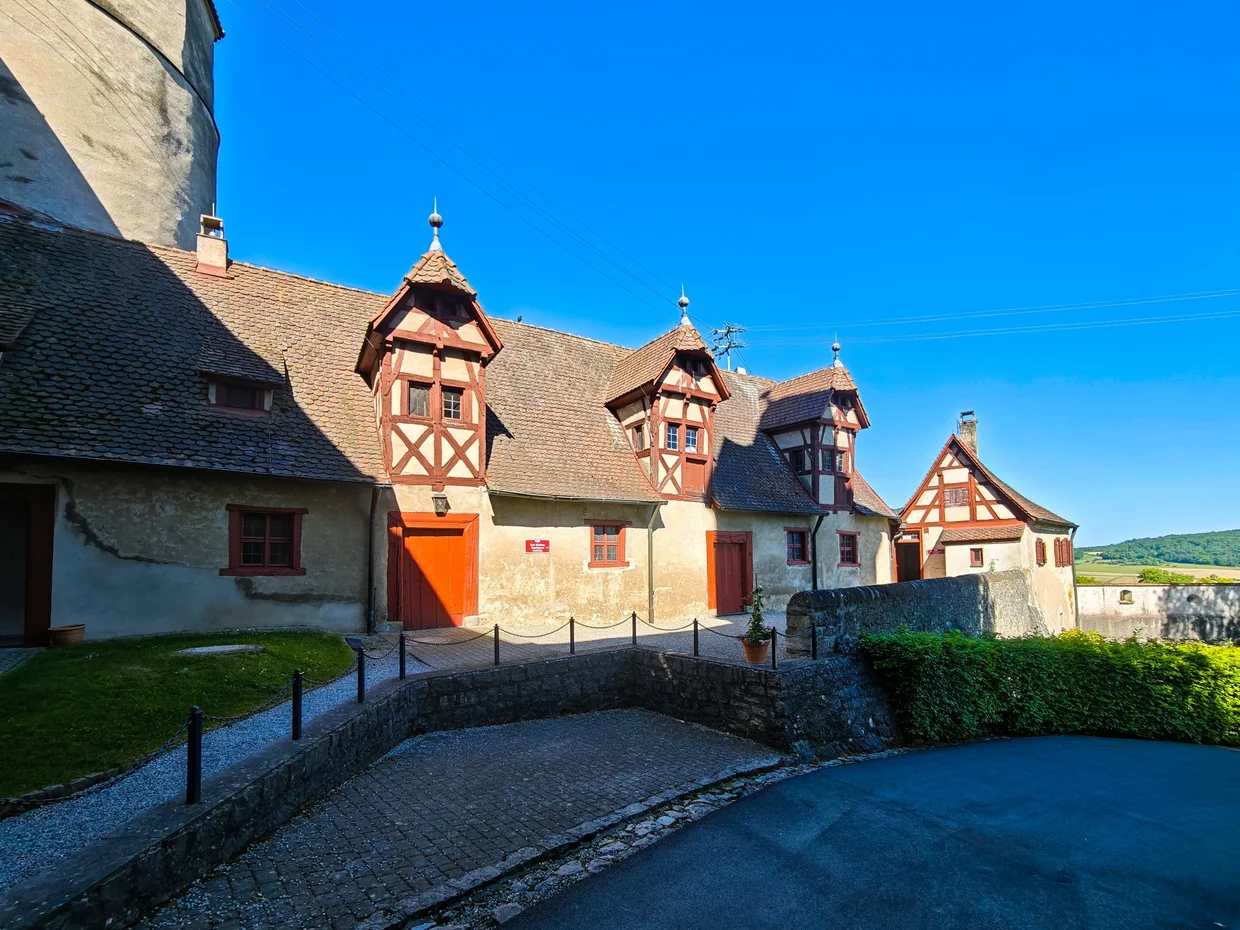 Half-timbered castle outbuildings under a deep blue sky