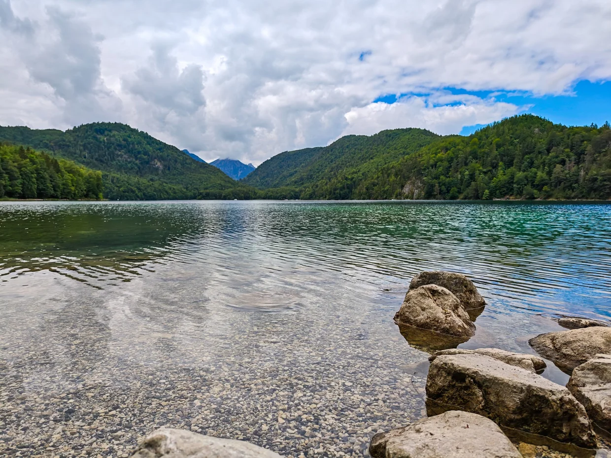 White boulders on the Alpsee shore with clear water