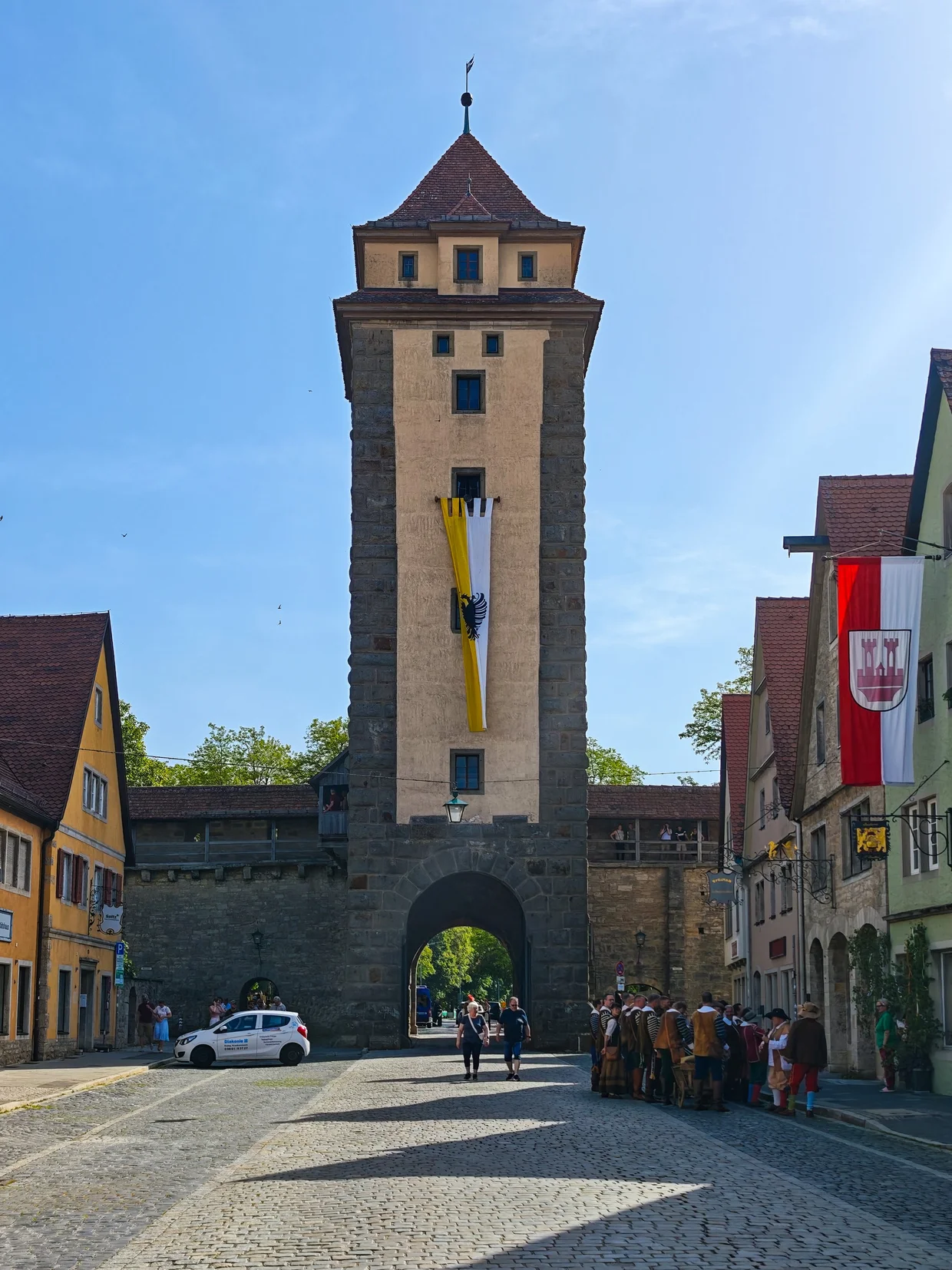 Crowd in costume below a gate tower