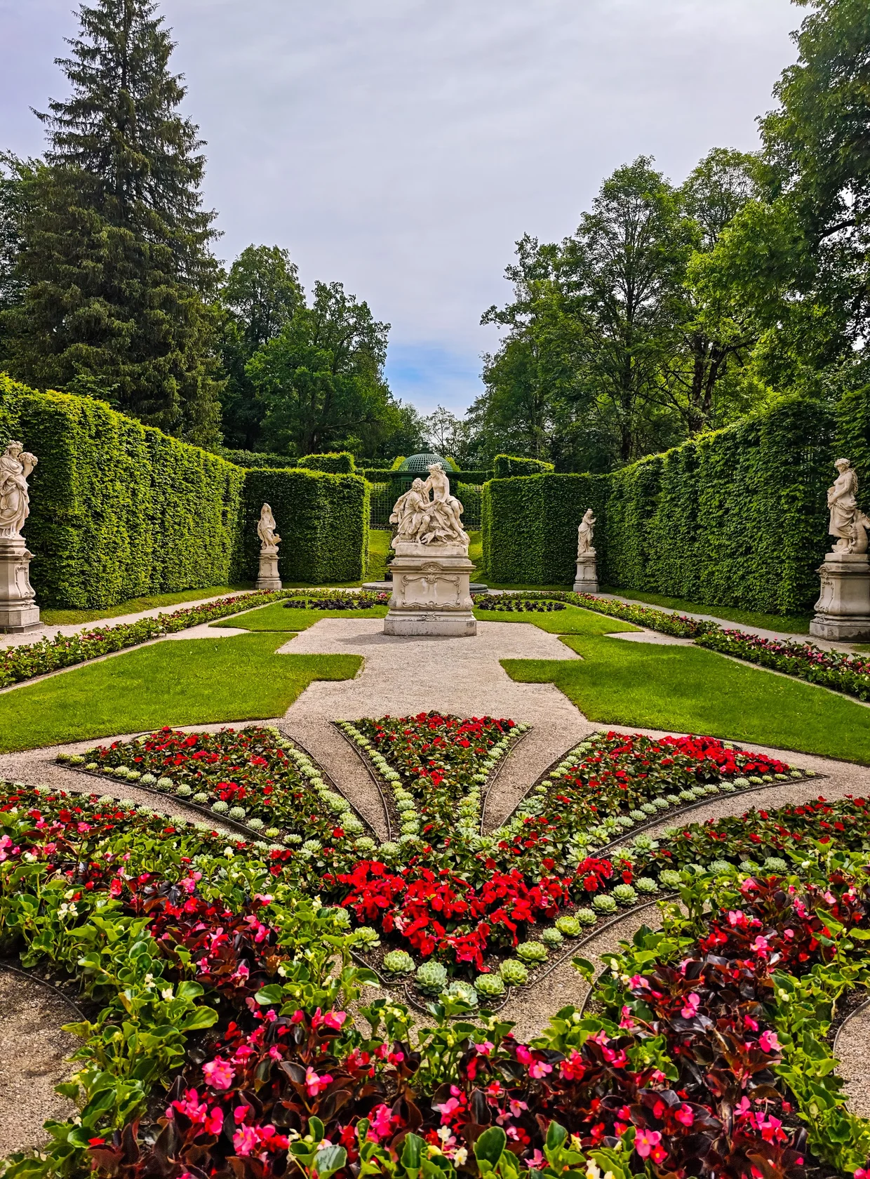 A hedged garden room with statues and flower beds
