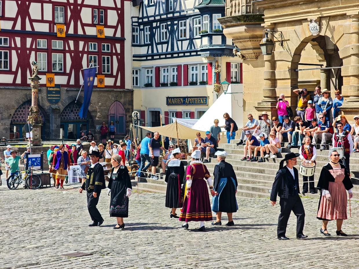 A tour group below a tall gable house