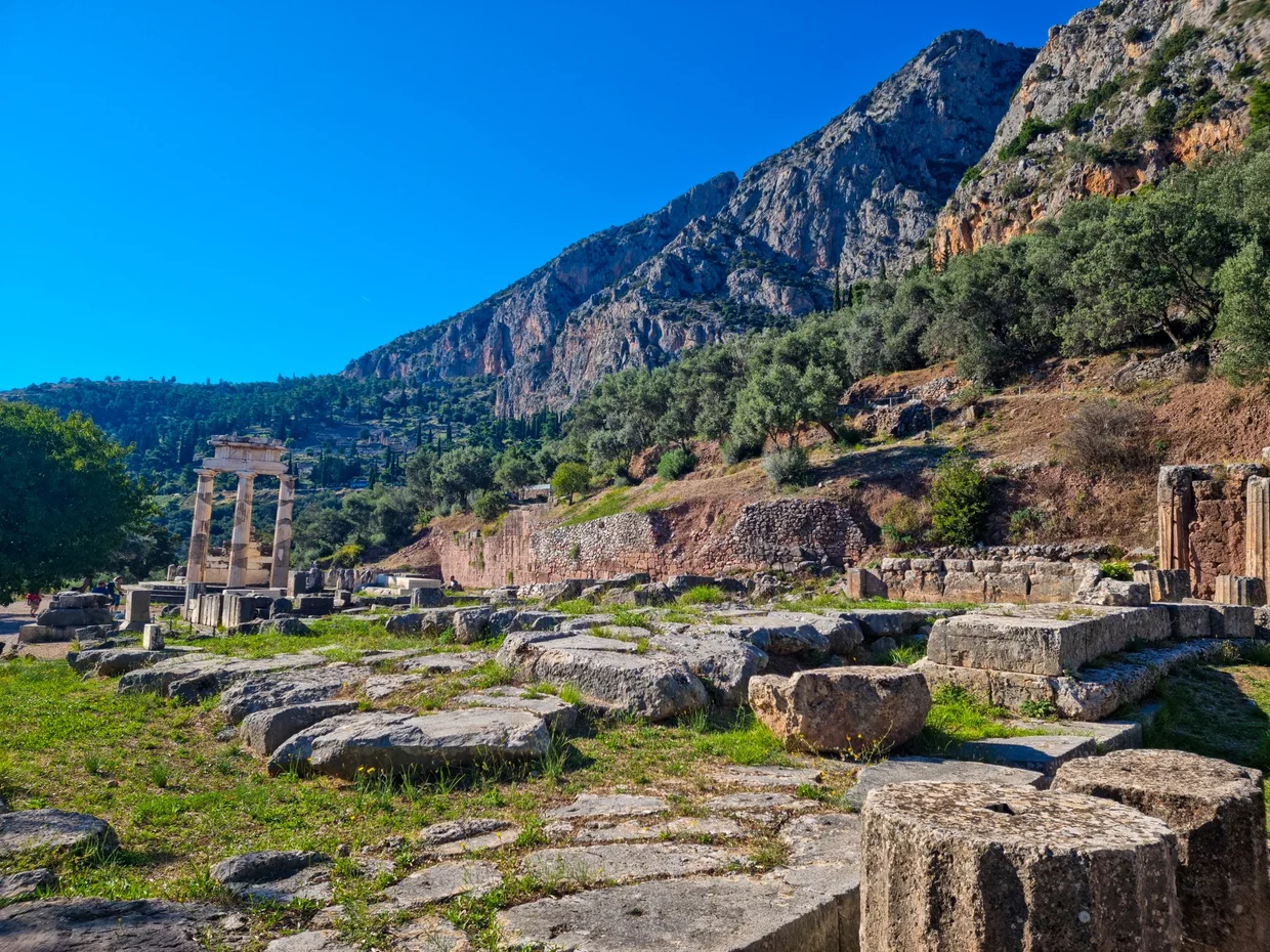 Sanctuary of Athena Pronaia with Tholos columns visible behind ruined foundations