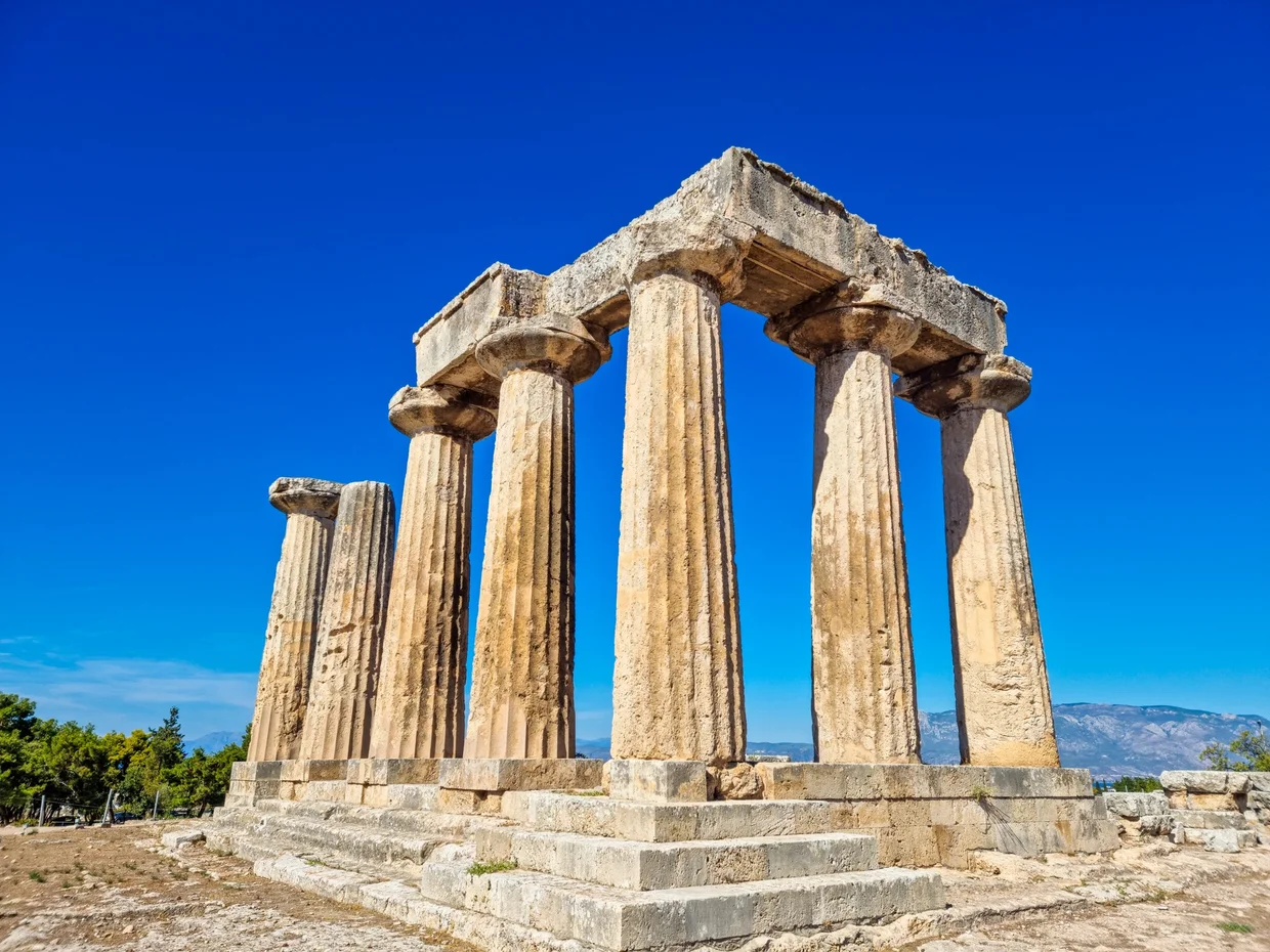 Temple of Apollo at Ancient Corinth, seven Doric columns standing against blue sky