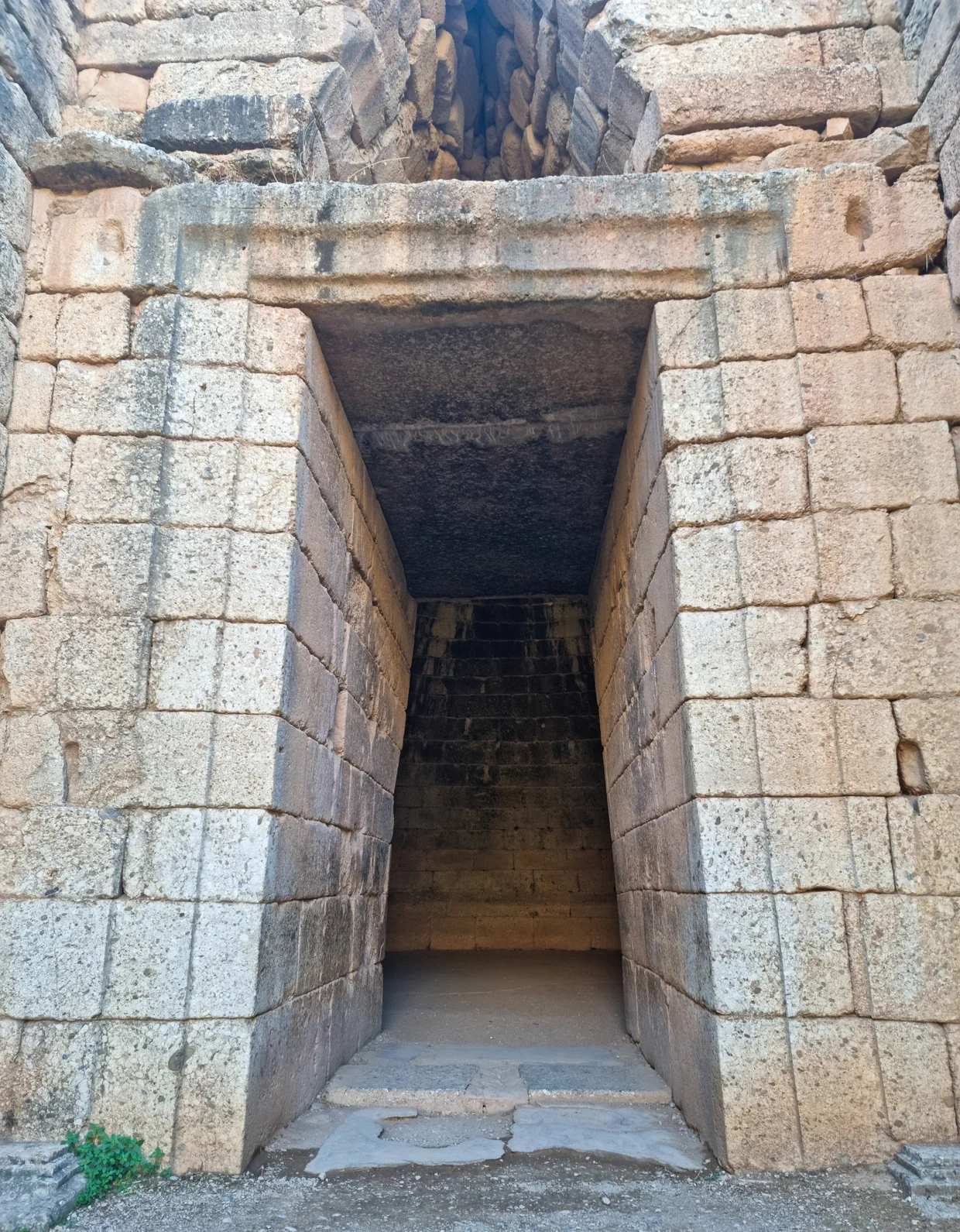 Massive stone entrance to the Treasury of Atreus with a towering lintel block above the doorway