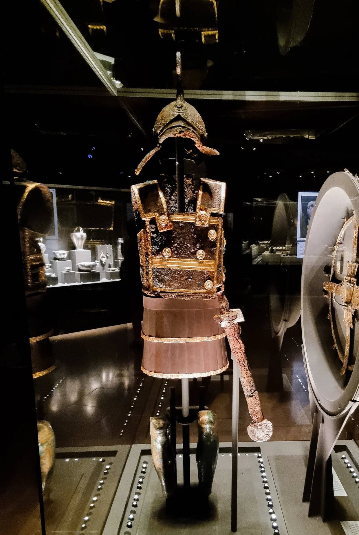 Reconstructed iron and gold cuirass with helmet and ceremonial sword on display