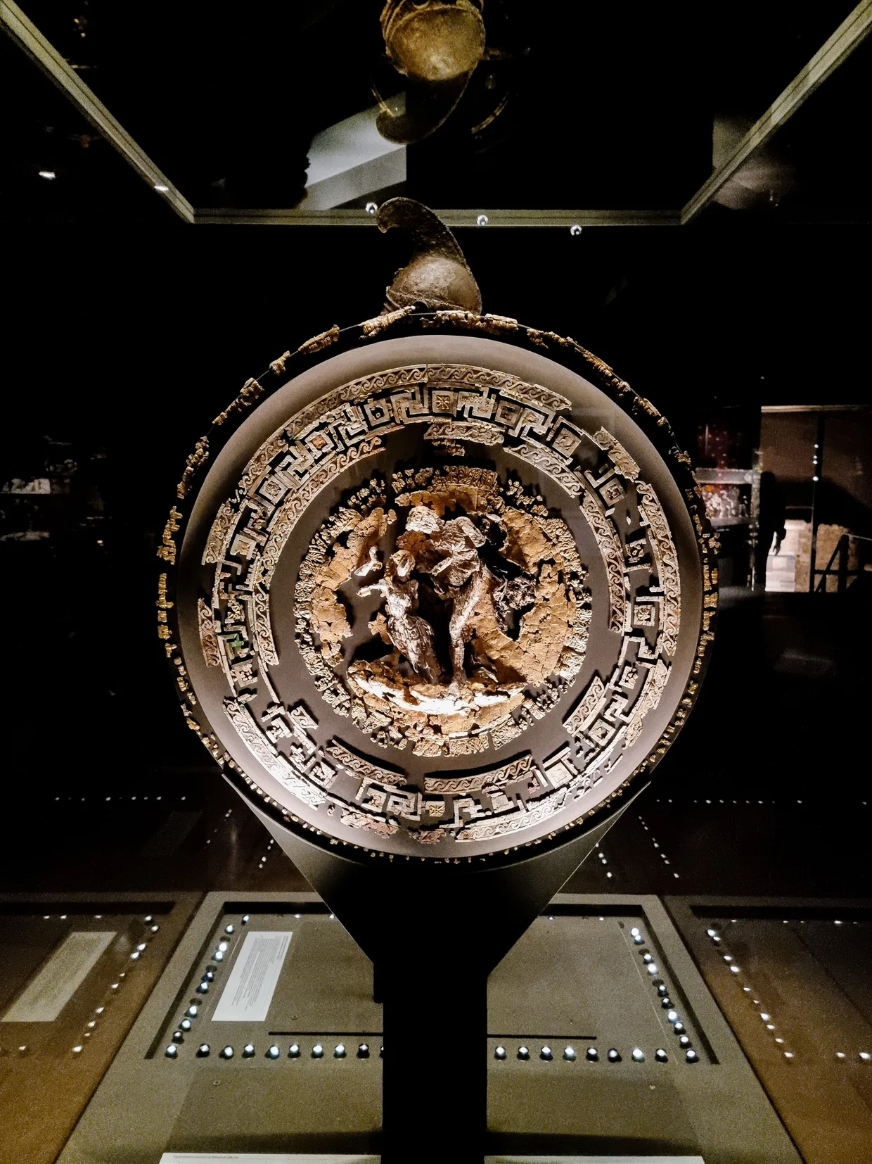 Round ceremonial shield with a central figural relief inside a Greek key border