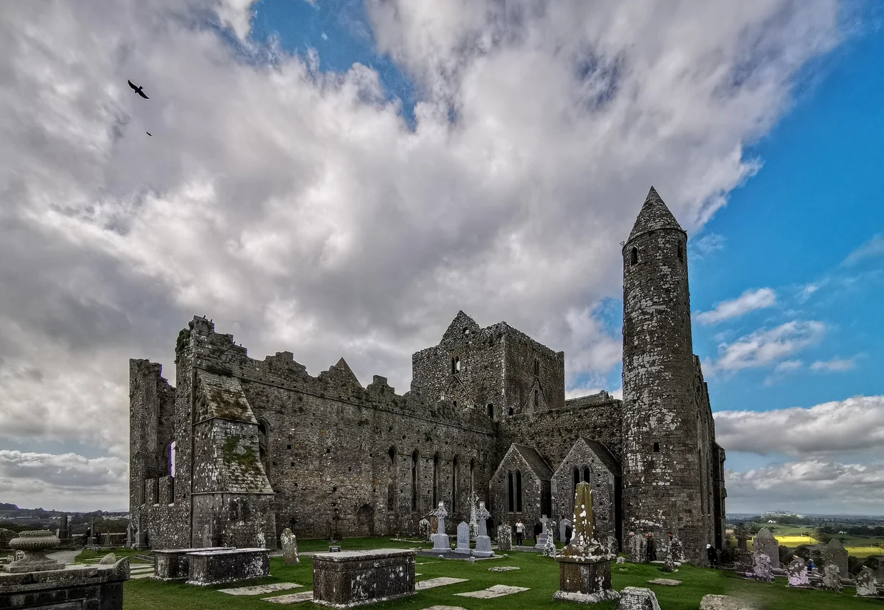 The Rock of Cashel with its round tower and roofless cathedral under dramatic clouds