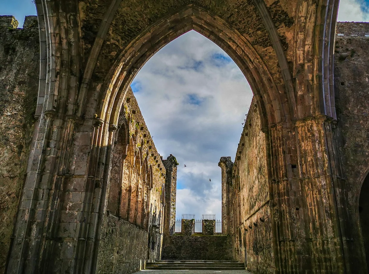A tall Gothic arch framing the open sky inside the roofless cathedral at the Rock of Cashel