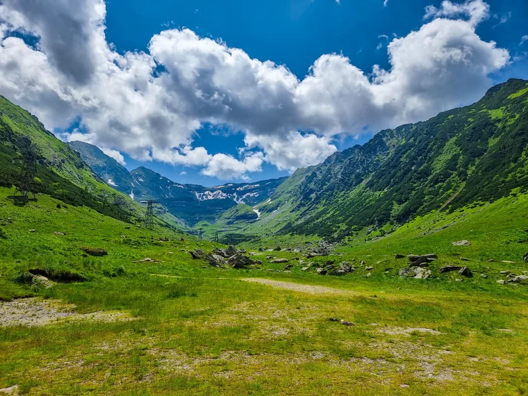 Wide green Fagaras valley with grassy slopes and scattered clouds