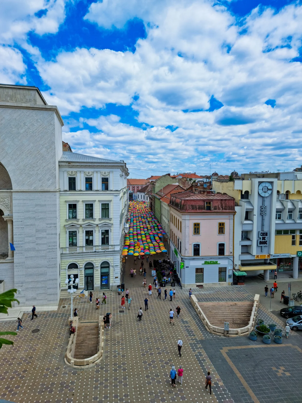 Victory Square with cafe-lined facades under a streaky sky