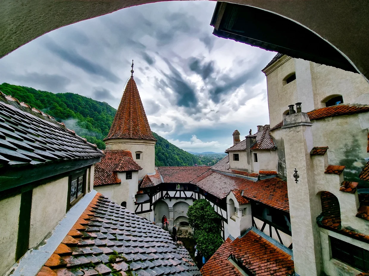 Bran Castle's roofs and tower under moody clouds