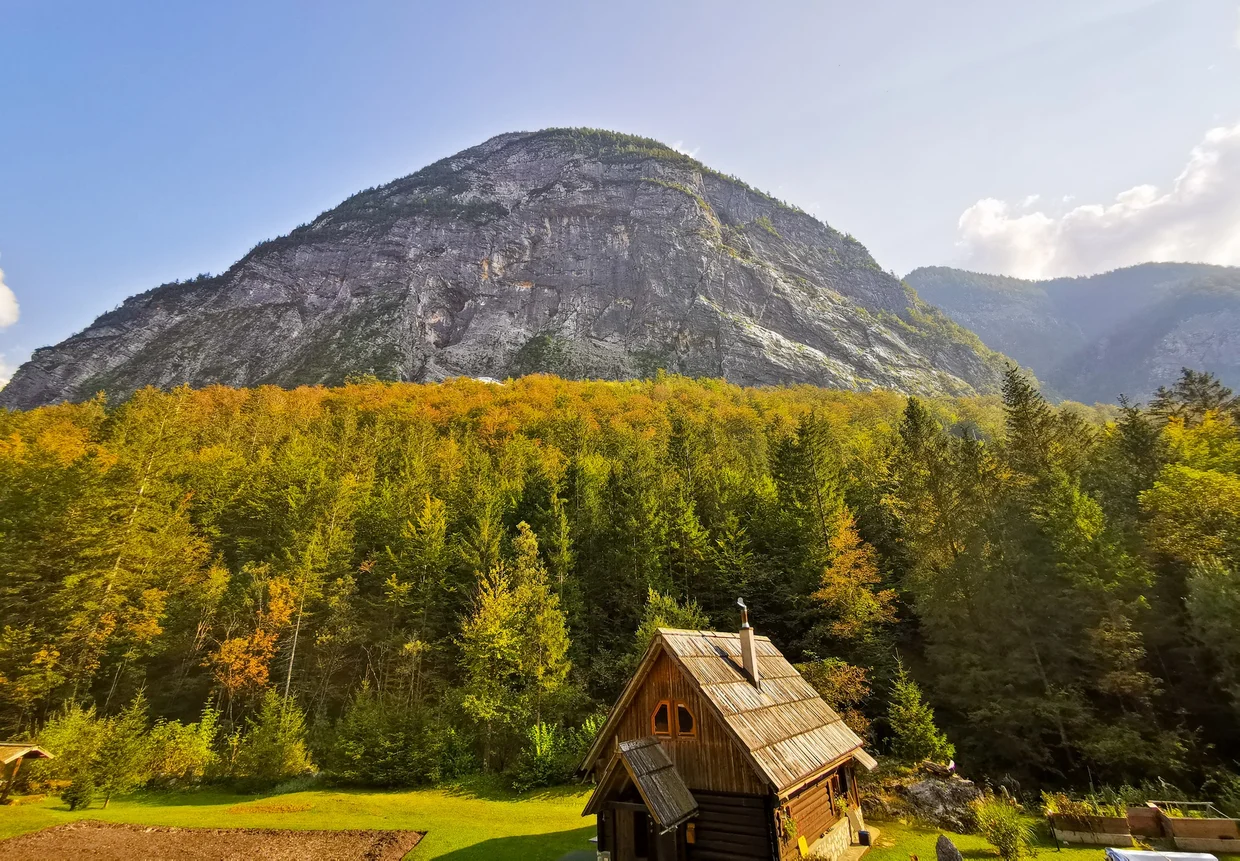 A small wooden Alpine Association hut below a rounded mountain