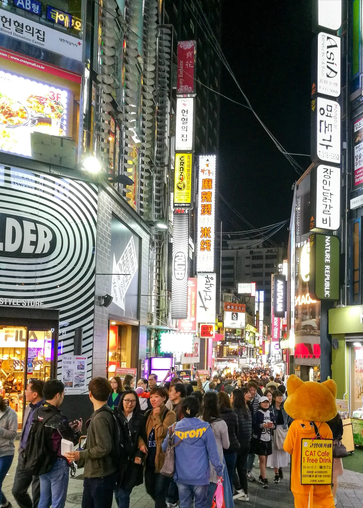 Crowded Myeongdong shopping street at night with neon signs in Korean