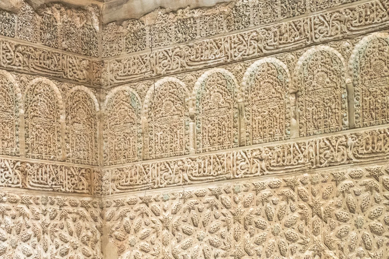 Intricate carved stucco wall with Arabic calligraphy