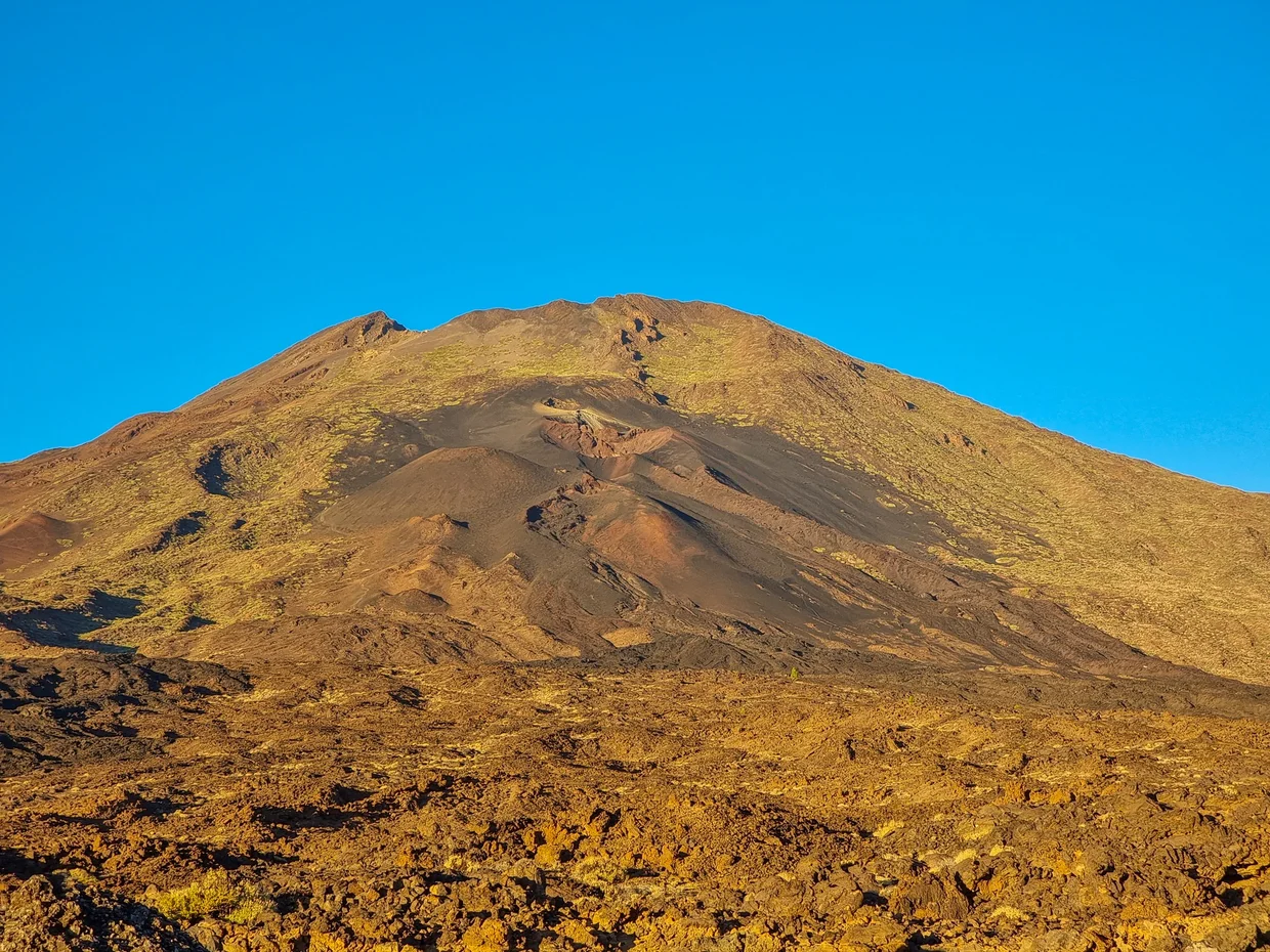 Mount Teide in warm golden sunset light, lava field in the foreground