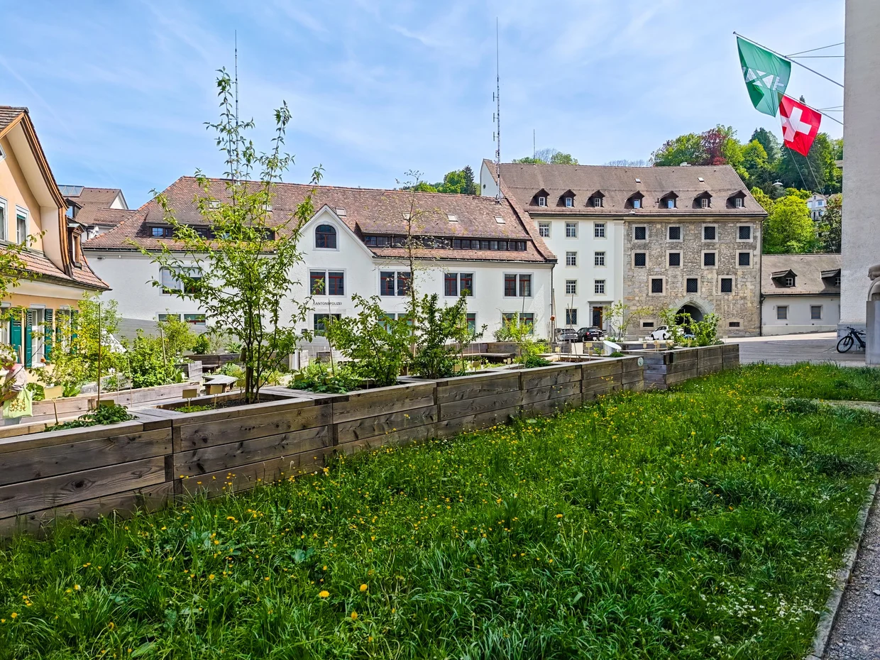 Quiet inner garden looking up at the abbey buildings with a Swiss flag
