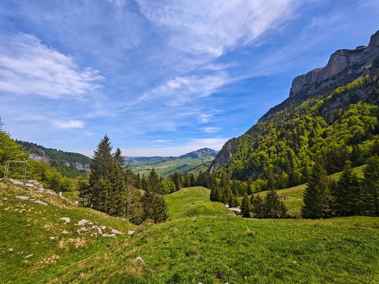 View down a winding alpine road into a wide green valley in north-east Switzerland