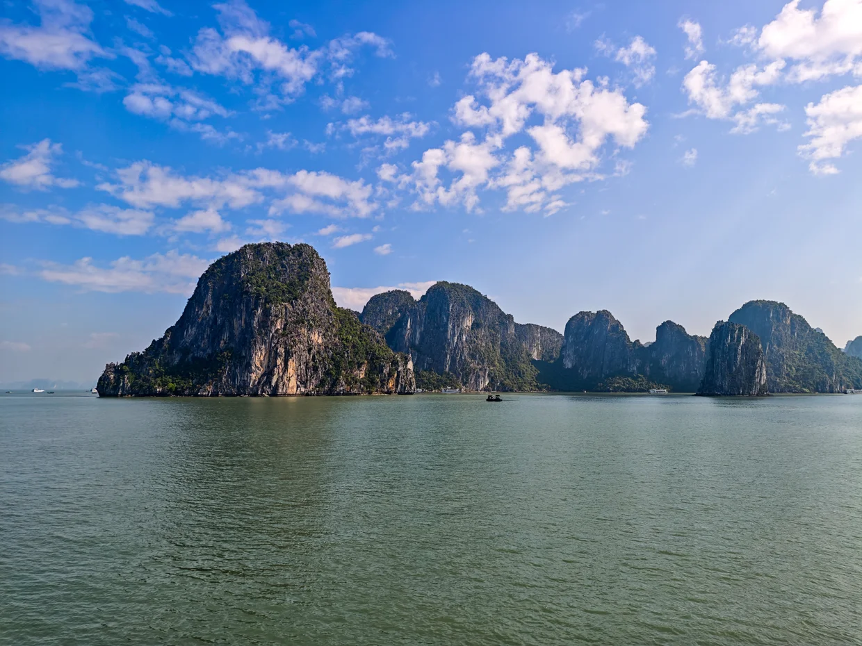 Close-up of steep limestone karst cliffs rising vertically from the calm sea in Ha Long Bay, Vietnam