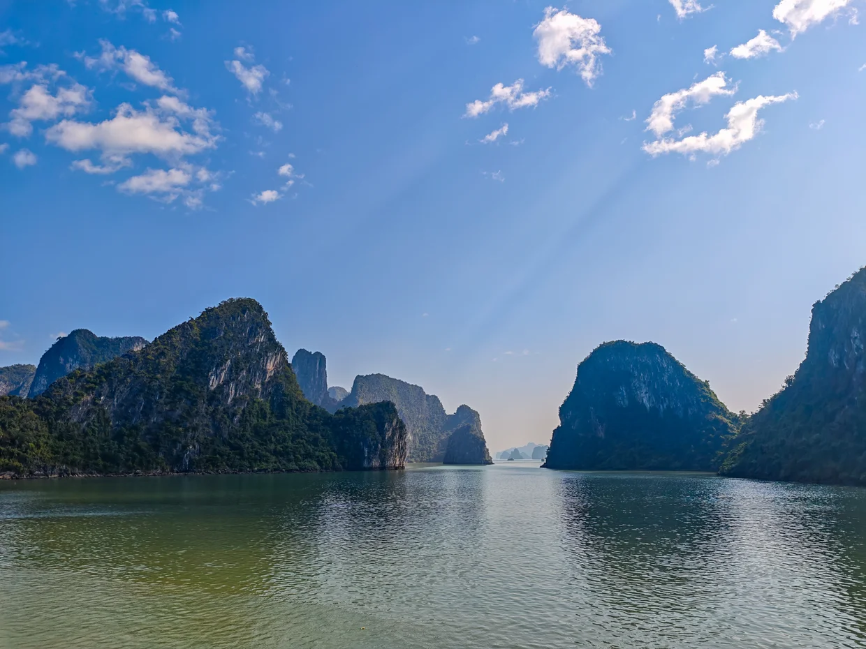 Ha Long Bay horizon with layered karst silhouettes fading into the distance over calm green water